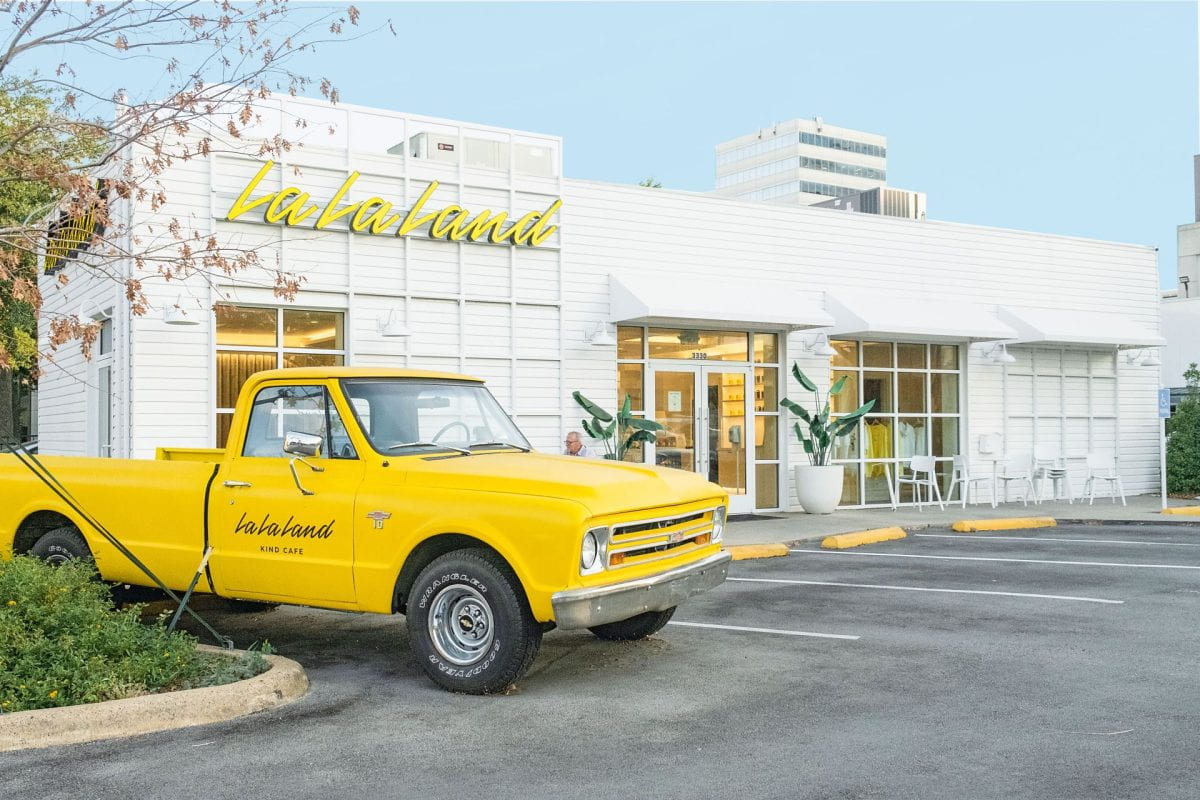 Photo of a bright yellow truck parked in front of a La La Land Kind Cafe